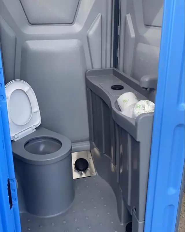 Interior of a flushing porta potty with grey seat and built-in sink