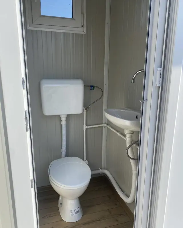 Inside a white VIP restroom cabin with flush toilet and small sink